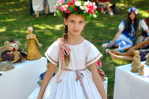 A pretty little girl is in a national white floral dress