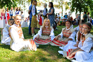 A group of charming Belarusian young girls are sitting on the grass