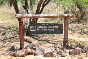 An inscription on a wooden sign board reads: “Bird Hide, remain silent to see more”