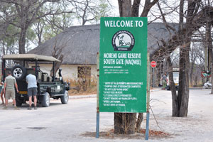 An information board reads: “Welcome to Moremi Game Reserve, South Gate (Maqwee)”