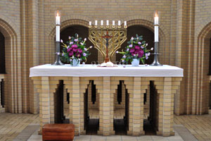 The altar table is decorated with the menorah (the seven-lamp ancient Hebrew lampstand) and flowers