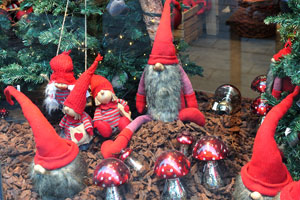 A bright shop window is decorated with trolls in red hats