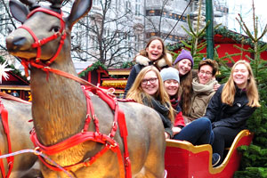 Young lovely women are smiling while sitting inside a deer harness at the Christmas market on Højbro Plads square