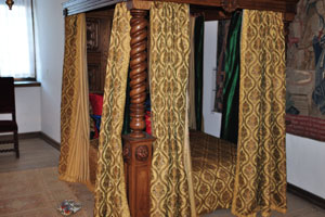 There is a vintage bed with curtains in the Royal chambers of Kronborg castle