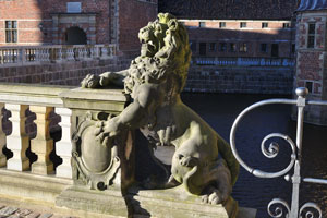 A stone lion statue is situated at the gates of the Frederiksborg Museum