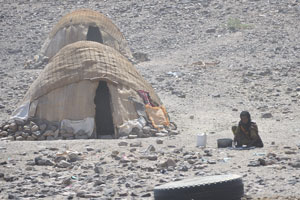 Afar woman works while sitting near the domed nomadic hut