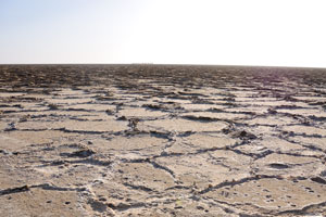 Salt plain with a Lunar landscape, one may see the camel caravan in the distance