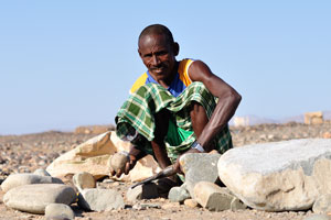 Afar craftsman works with a small boulder