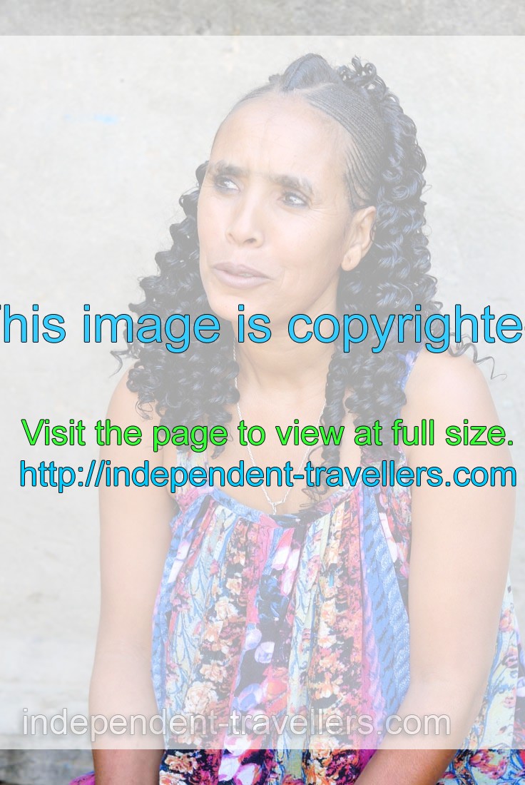 Woman has a hairstyle with african braids and a colourful dress