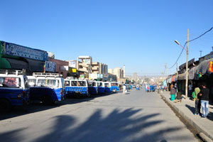 There are many vehicles on the street near the market