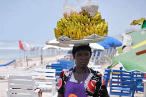 A female vendor keeps the huge plate full of bananas on the head
