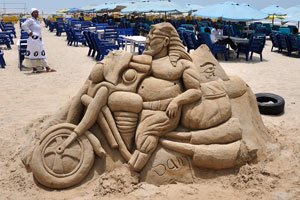 Sand sculpture of a motorcyclist is made on the Labadi Beach