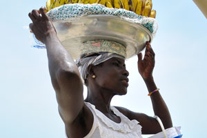 A female vendor of bananas is going to remove the tray