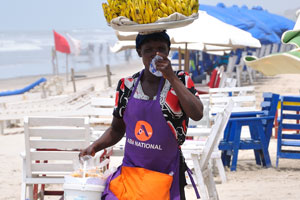 A female vendor selling bananas is on the beach
