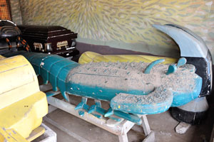 A coffin in the shape of a blue scorpion is in the Kane Kwei Carpentry Workshop