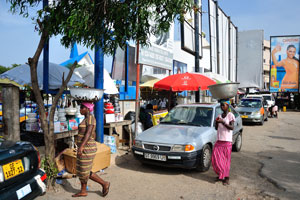 Vendors with the bowls on their heads are on the parking place of Makola market