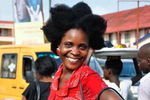 A beautiful woman with an awesome hairstyle is smiling and posing for me