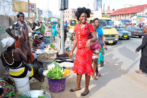 A good-looking woman in the red dress is on the Makola market