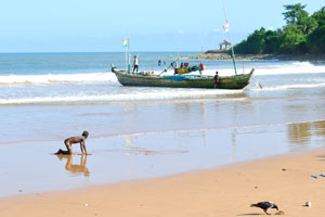 A boy and a crow are on the Busua beach
