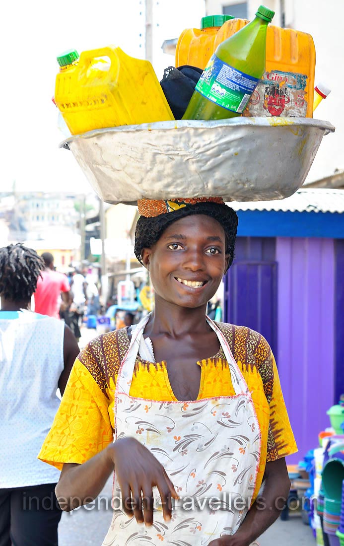 A lovely Ghanaian young woman smiles at me while carrying the basin full of plastic jerry cans