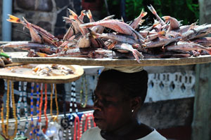 A woman is carrying the tray of fish on the head