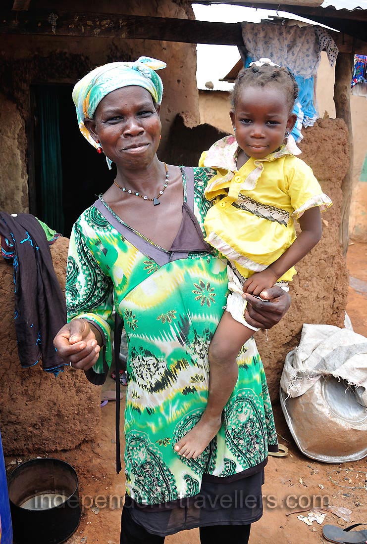 A lovely mother and her daughter are at the entrance to their hut
