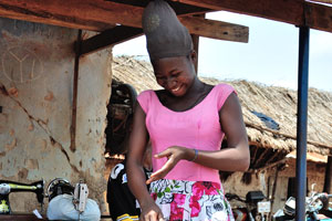 A lovely Ghanaian girl wears a colourful skirt and a weird headdress made of a nylon stockings