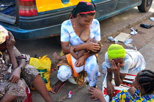 A mother is breastfeeding a child on the street