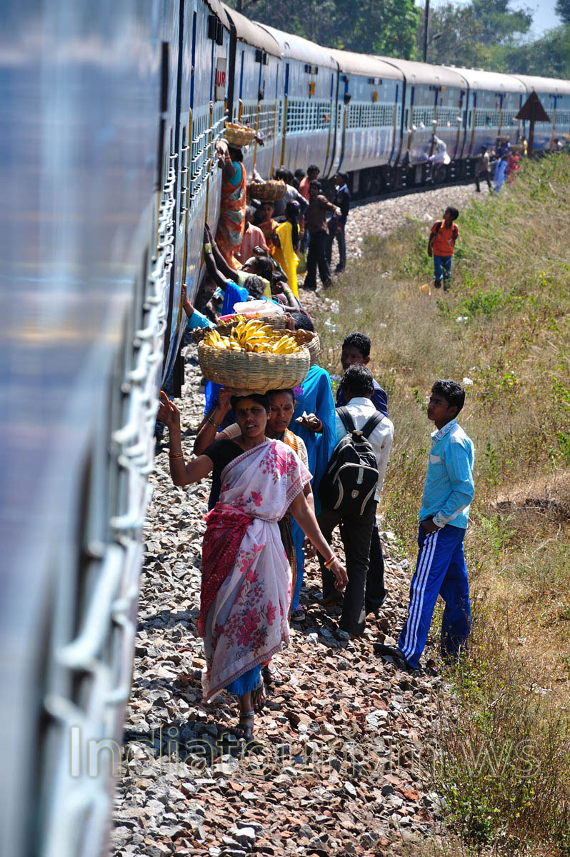 women carry baskets of bananas to a train on their heads