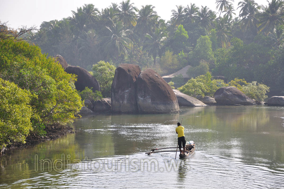 Indian man propels the thin boat by long pole