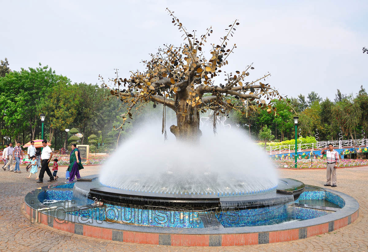 The tree with golden leaves inside the water fog fountain