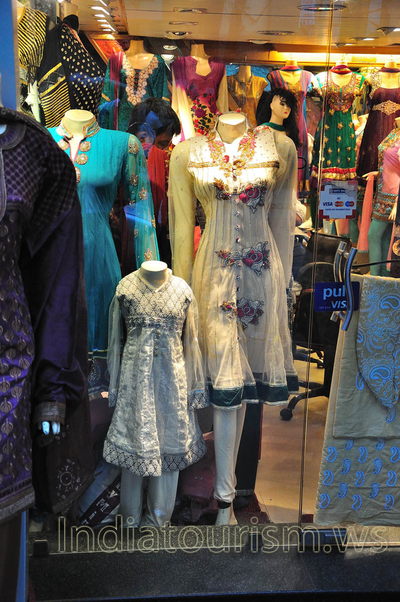 There are elegant dresses in the window of one of the shops