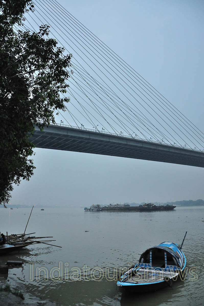 The ship is sailing under the bridge