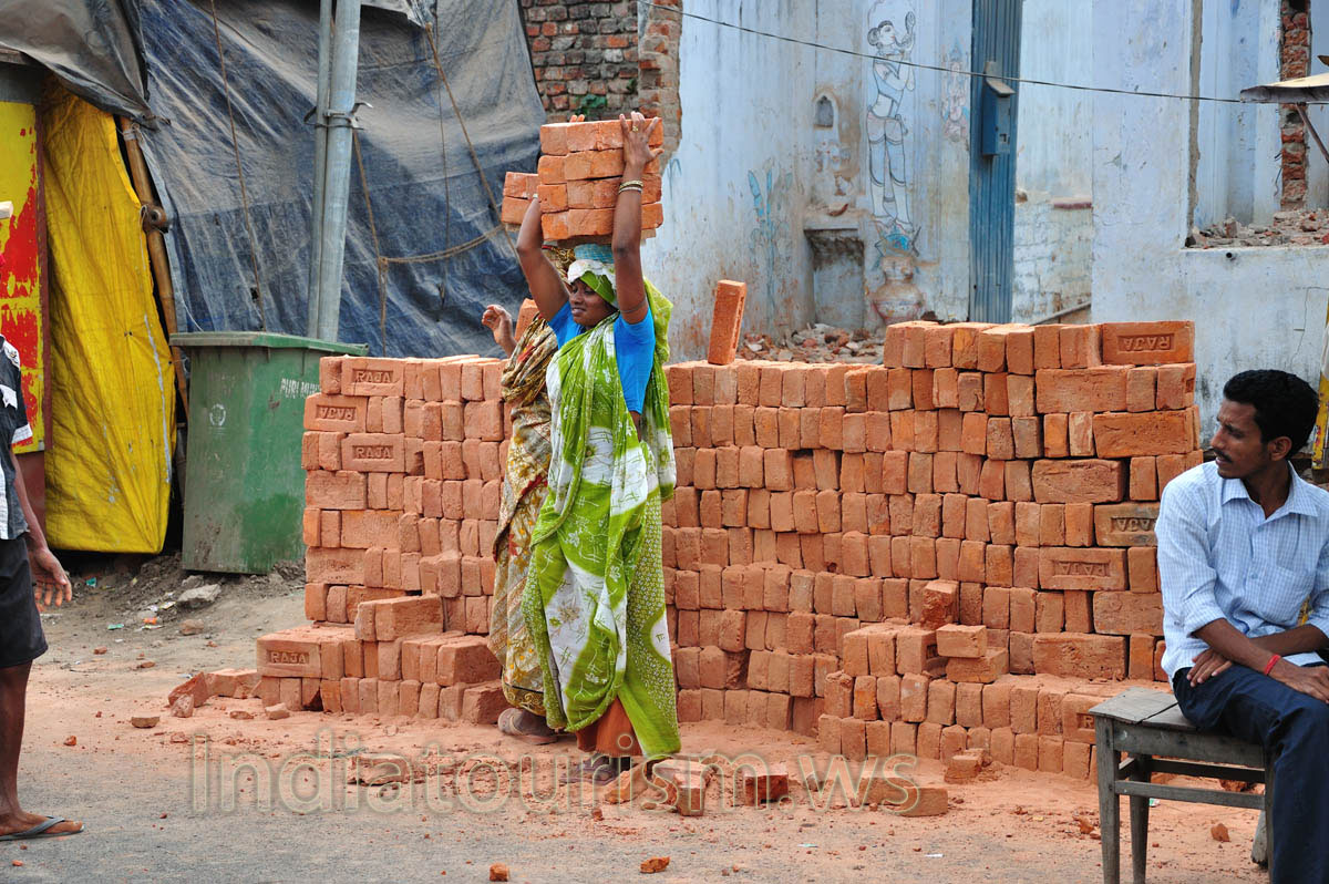 Woman is carrying the bricks on the head