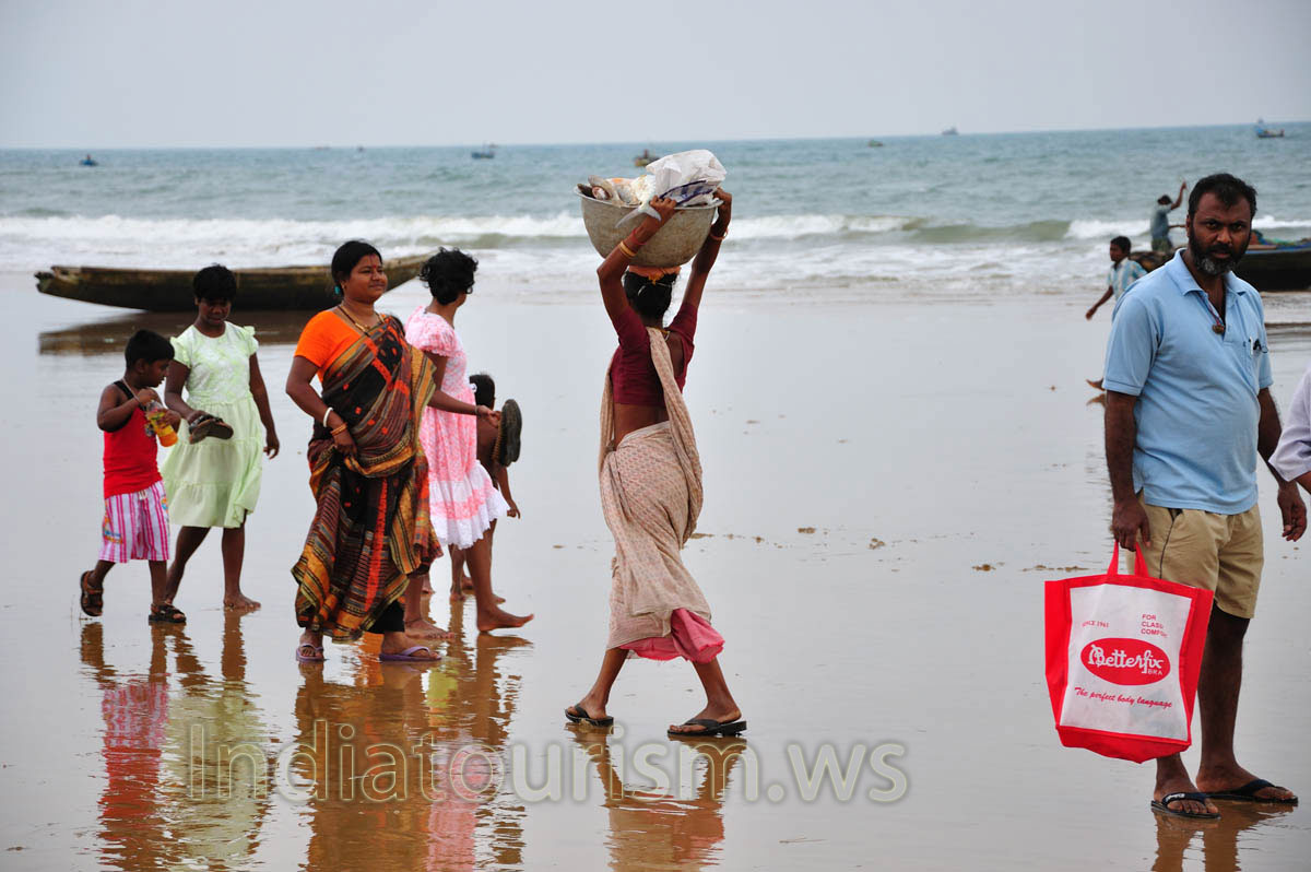 A woman carries a fish in a bucket on her head
