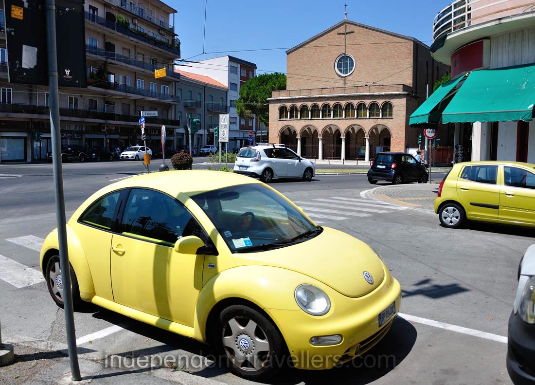 The tiny yellow Volkswagen is parked near the church of San Nicolo