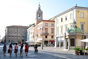 Piazza Tre Martiri is a bustling city square with a clock tower, a statue of Julius Caesar, shops and cafes