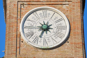 A clock face of the traditional type is on the tower of the Piazza Tre Martiri