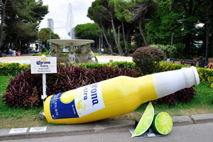 Corona Extra advertising statue with the shape of a bottle is located near the fountain