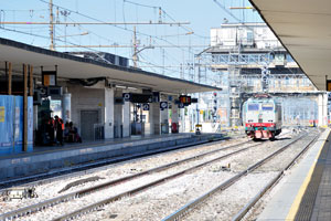 An electric locomotive runs along the rails of Bologna Centrale railway station
