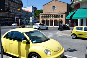 The tiny yellow Volkswagen is parked near the church of San Nicolo