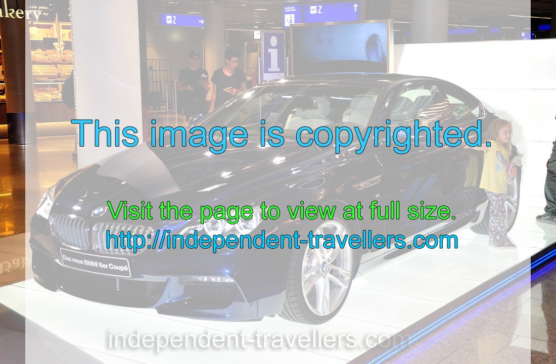 Little girl wants to be photographed on the background of the “Das neue BMW 6er Coupe” automobile in the FRA airport