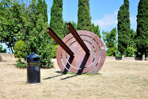 A strange metal monument and a litter bin beside are in the public park of Albornoz Fortress