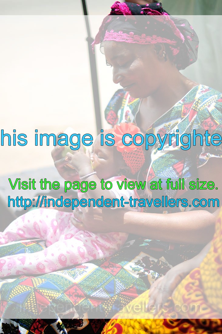 Ivorian woman is feeding her baby with watermelon