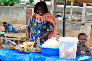 A beautiful female vendor adds some fresh onion to the tasty roasted fish