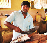 A male fish vendor cuts tuna