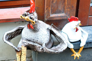 A stylish rooster with a hen are sitting at the entrance to a shop