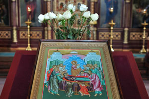The icon is decorated with white roses in the Cathedral of the Theotokos