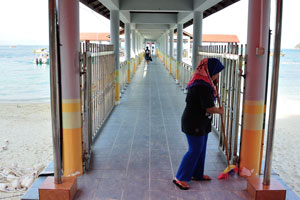 Young malaysian woman cleans the long pier which belongs to ministry
