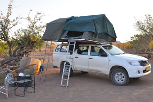 Car roof top tents are fully unfolded at the camping pitch in Palm Camp